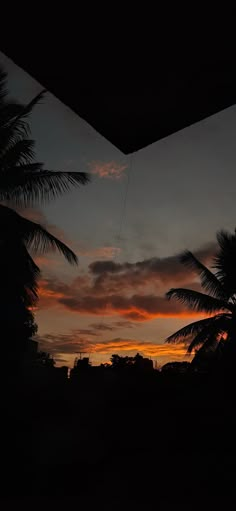 the sun is setting behind some palm trees