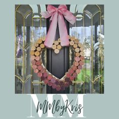 a wreath made out of wine corks with a pink bow hanging on the front door