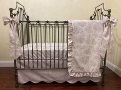 a baby crib with pink and white bedding on top of it's wooden floor