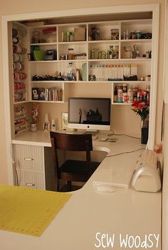 a desk with a computer on top of it next to a book shelf filled with books