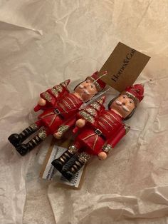 three red wooden nutcrackers sitting next to each other on top of a piece of paper