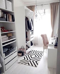 a white closet with lots of clothes and shoes on the shelves next to a window