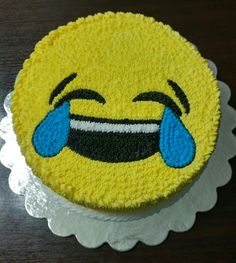 a smiley face cake sitting on top of a white doily with blue and black icing