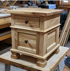 a wooden table with two drawers on it and some woodworking tools in the background