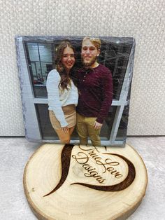 a couple standing next to each other in front of a wooden plaque