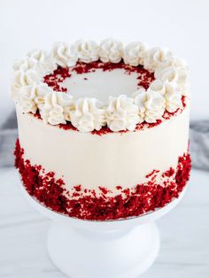 a red velvet cake with white frosting and sprinkles on a pedestal