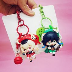 two keychains with anime characters on them are being held by someone's hand