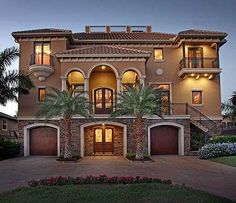 a large house with two garages and palm trees in the front yard at dusk