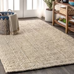 a large rug in the middle of a living room with a basket on the floor