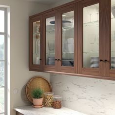 a kitchen with wooden cabinets and white marble counter tops, along with a potted plant