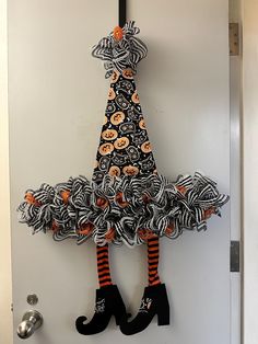 a door hanger decorated with black and orange yarn, pumpkins and striped socks