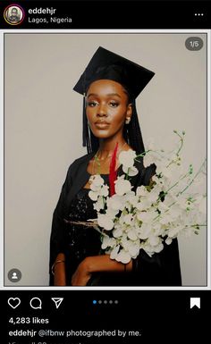 an instagram photo of a woman in her graduation cap and gown holding white flowers