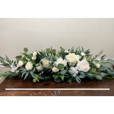 white flowers and greenery are arranged in a wooden box on top of a table