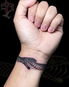 a hand with a wrist tattoo that has a snake on it and is holding up the arm