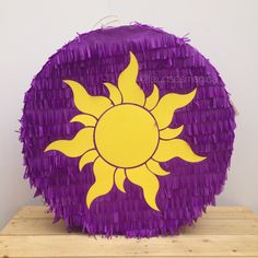 a purple and yellow pinata sitting on top of a wooden table next to a white wall