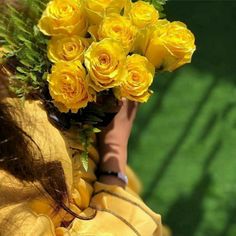 a woman holding a bouquet of yellow roses