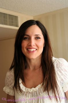 a woman with long brown hair smiling at the camera