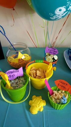 there are many cups and bowls with food in them on the table next to balloons