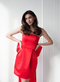 a woman in a red dress posing for the camera with her hands on her hips