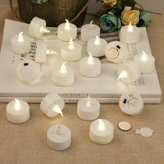 several white candles sitting on top of a book