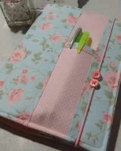 a pink and blue flowered notebook with buttons on it