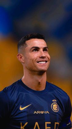 a soccer player is smiling and wearing a blue shirt with gold lettering on it's chest