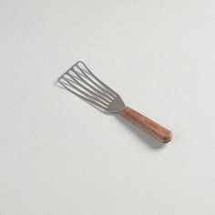 a metal fork with wooden handles on a white surface