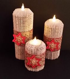 three white candles with red bows on them sitting next to each other in front of a black background