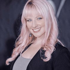 a woman with pink hair smiling for the camera