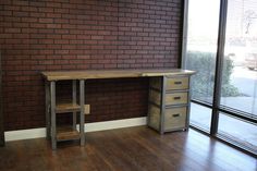 a wooden desk sitting in front of a brick wall next to a sliding glass door