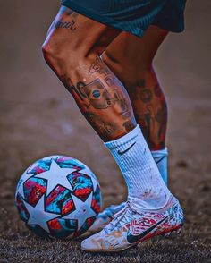 a person with tattoos standing next to a soccer ball