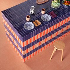 a table with plates and bowls on it in the middle of an orange, blue and white tiled floor