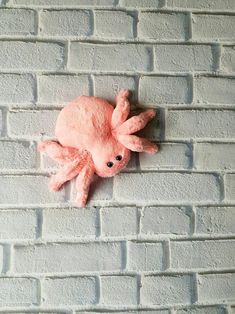 an octopus stuffed animal on a brick wall