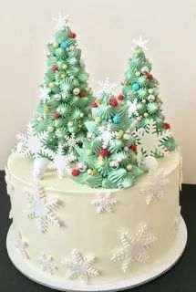 a white cake with green frosting decorated with snowflakes and small trees on top