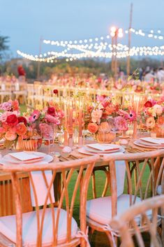 a table set up with flowers and candles for an outdoor wedding reception in the evening