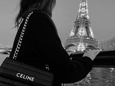 a woman is looking at her cell phone in front of the eiffel tower