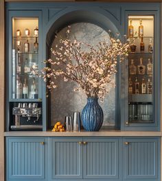 a vase filled with flowers sitting on top of a counter next to liquor bottles and glasses