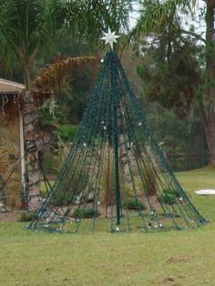 there is a christmas tree made out of wire and balls in front of a house