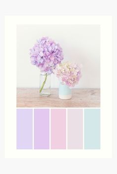 two vases filled with purple flowers on top of a wooden table in front of a white wall