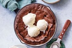 two scoops of ice cream sit on top of a chocolate cake in a pan