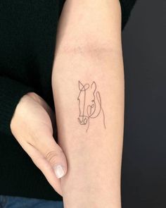 a woman's arm with a small tattoo of a horse on the left side