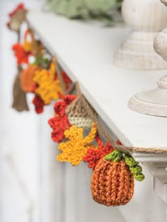 crocheted pumpkins and leaves are hanging on the mantle