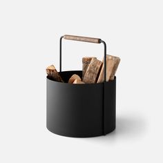 a black basket filled with logs and a wooden stick in it's holder on a white background