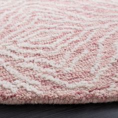 a pink and white rug on top of a wooden floor next to a black table