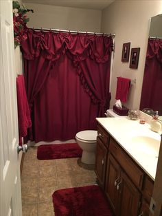 a bathroom with red shower curtains and rugs