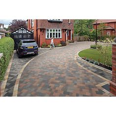 a car is parked in front of a brick house with a driveway that has been paved