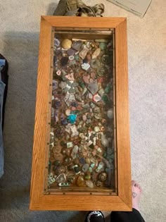 a wooden frame filled with lots of different types of rocks and pebbles on the floor