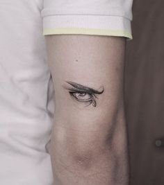 a woman's arm with an eye tattoo on the left side of her arm