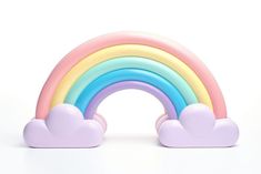 a rainbow shaped toy with clouds on the bottom, and a white background behind it