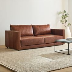 a brown leather couch sitting on top of a rug